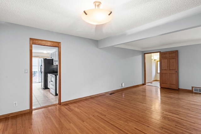 spare room with light hardwood / wood-style floors and a textured ceiling