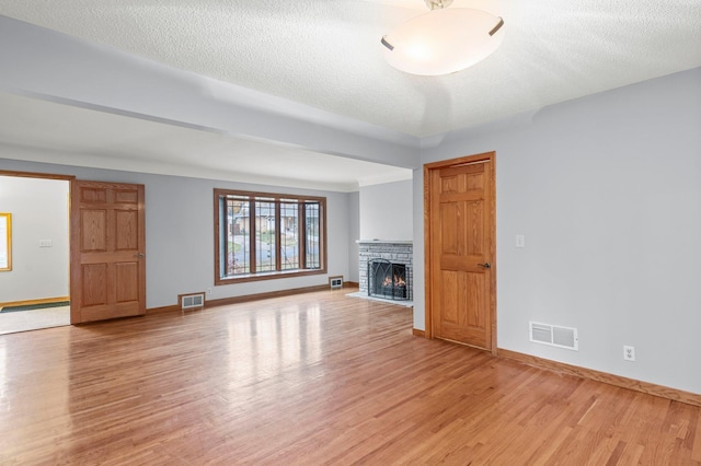 unfurnished living room with light hardwood / wood-style floors and a textured ceiling