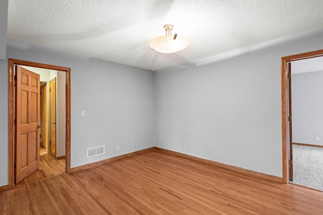 empty room featuring wood-type flooring and a textured ceiling