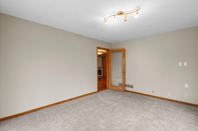 carpeted spare room with a textured ceiling