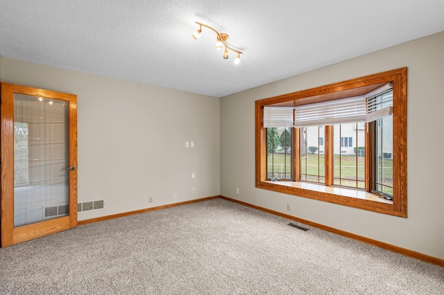 unfurnished room featuring carpet and a textured ceiling