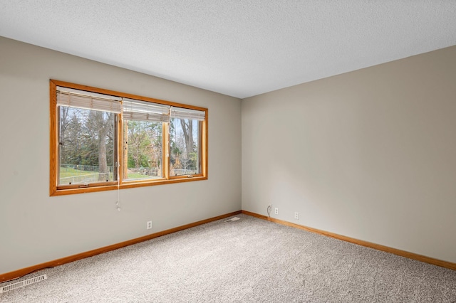 carpeted empty room featuring a textured ceiling