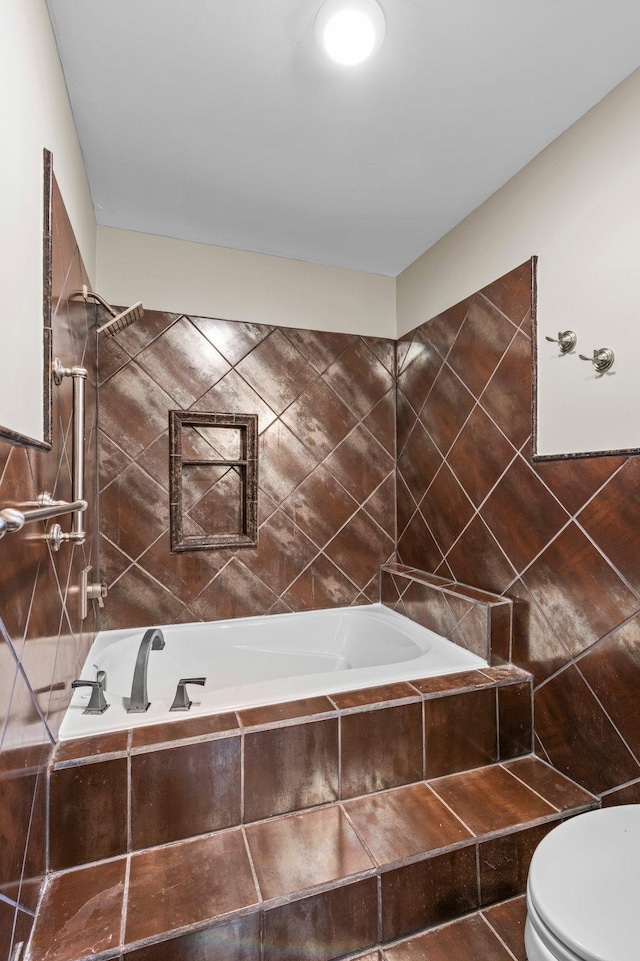 bathroom featuring tiled bath, tile patterned flooring, and toilet