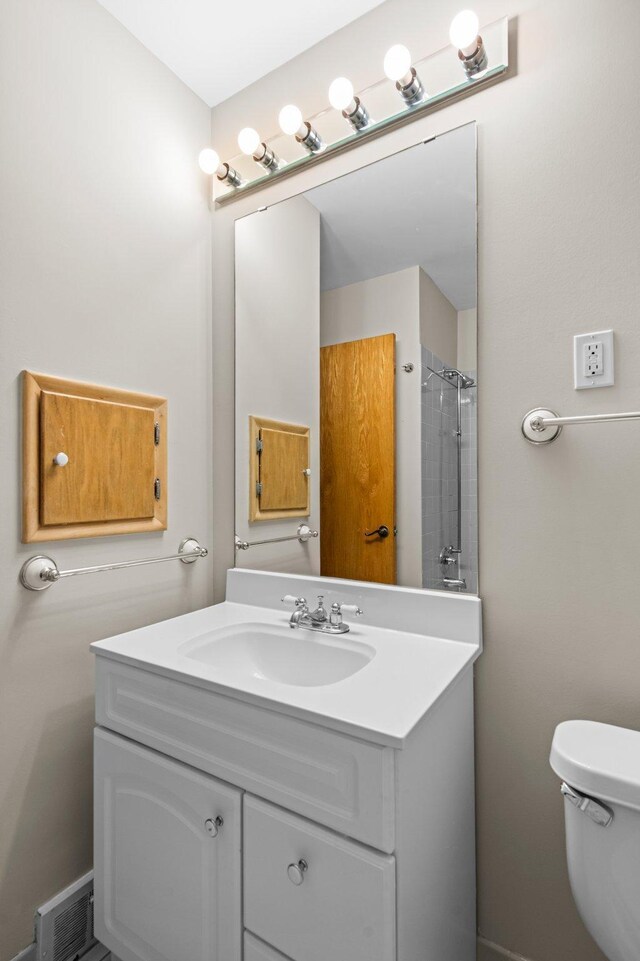 bathroom with walk in shower, vanity, and toilet