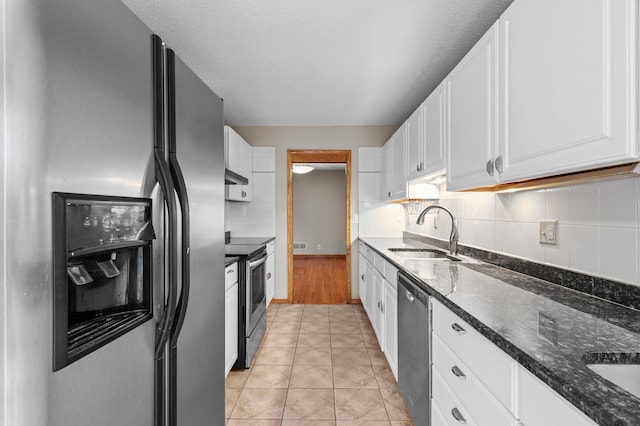 kitchen featuring white cabinets, appliances with stainless steel finishes, dark stone countertops, and sink