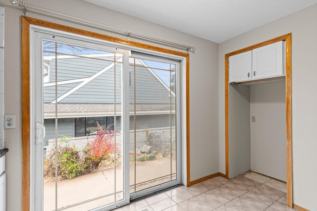 doorway with light tile patterned floors and a textured ceiling