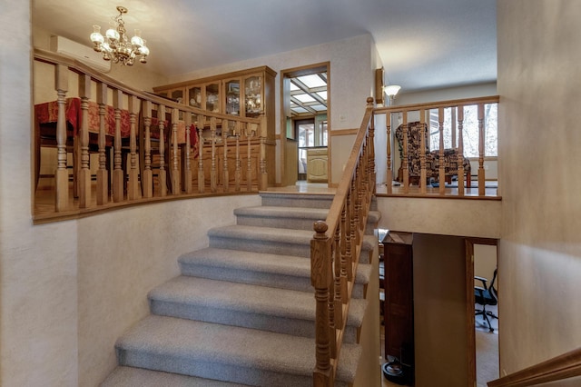 stairs featuring a notable chandelier and a wall mounted AC