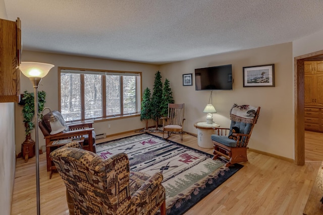 living room featuring light wood-style flooring, baseboards, and a textured ceiling