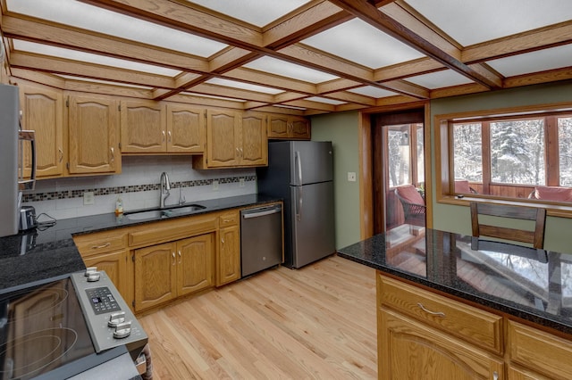 kitchen featuring light wood finished floors, coffered ceiling, stainless steel appliances, and a sink