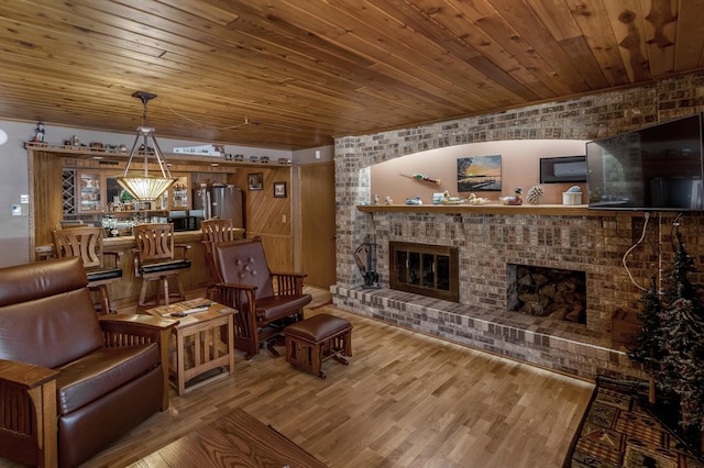 living room with wood finished floors, a brick fireplace, and wooden ceiling