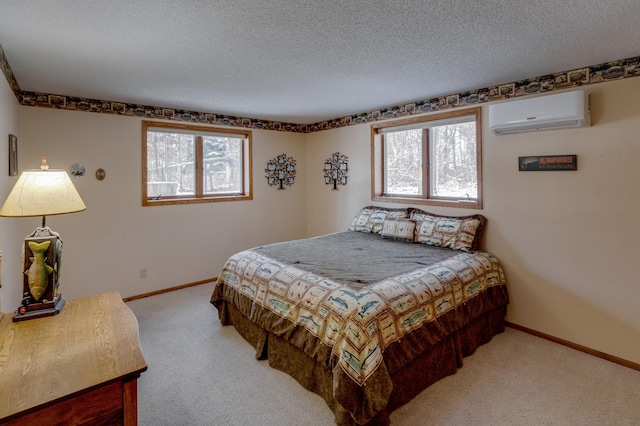 bedroom featuring light carpet, a textured ceiling, a wall mounted air conditioner, and baseboards