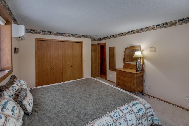 bedroom featuring a wall unit AC, baseboards, a closet, a textured ceiling, and carpet flooring