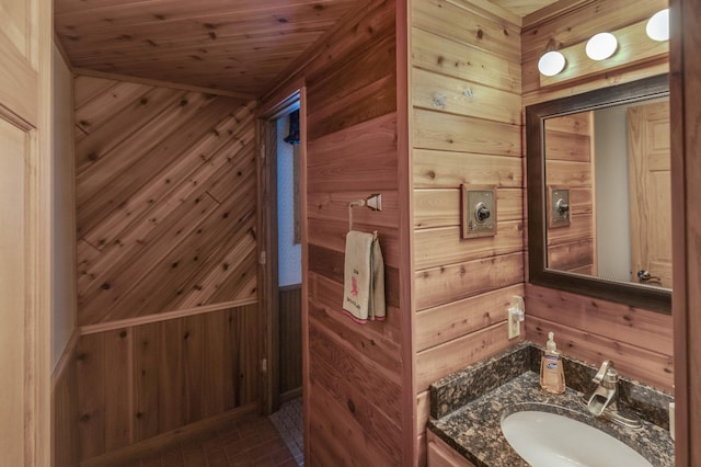 bathroom featuring vanity, wooden walls, wood ceiling, and brick floor