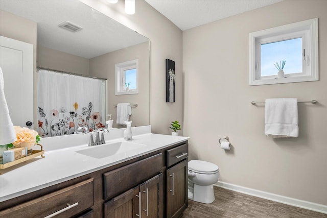 bathroom featuring wood-type flooring, vanity, a textured ceiling, and toilet