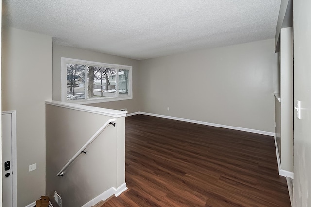 spare room featuring a textured ceiling and dark hardwood / wood-style floors