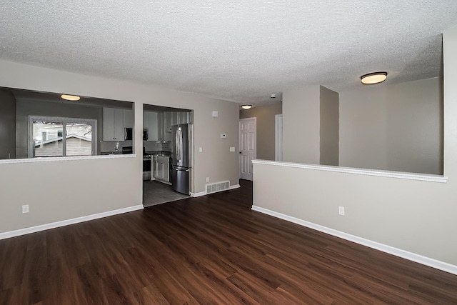 unfurnished room with a textured ceiling and dark hardwood / wood-style flooring