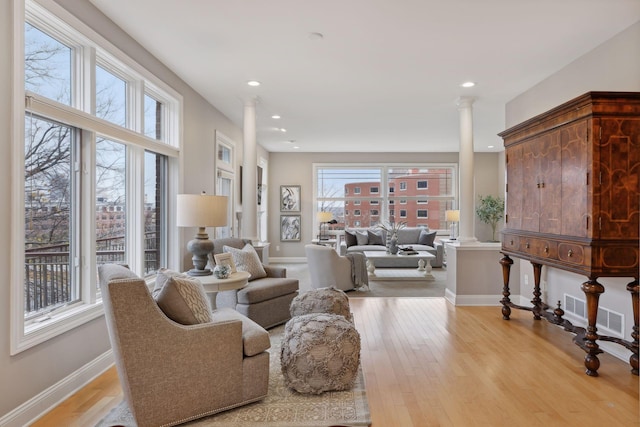 living room featuring light hardwood / wood-style floors and ornate columns