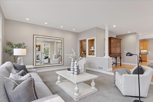 living room with decorative columns and light colored carpet