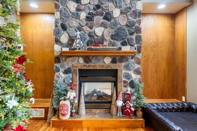 details featuring hardwood / wood-style floors, a stone fireplace, and wood walls