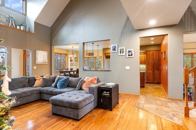 living room with a towering ceiling, light wood-type flooring, and a notable chandelier