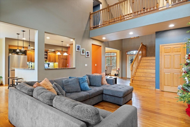 living room with light hardwood / wood-style flooring and a towering ceiling