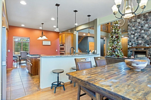 kitchen with light stone counters, double oven, kitchen peninsula, a fireplace, and light wood-type flooring