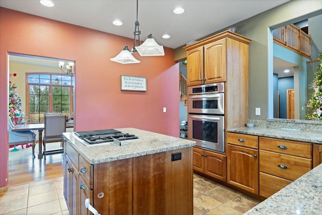 kitchen featuring appliances with stainless steel finishes, an inviting chandelier, hanging light fixtures, and light stone counters