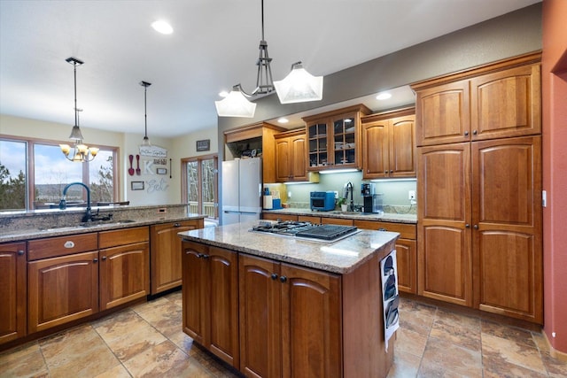 kitchen with white refrigerator, a kitchen island, hanging light fixtures, and stainless steel gas cooktop