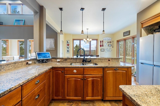 kitchen with a chandelier, light stone countertops, plenty of natural light, and sink