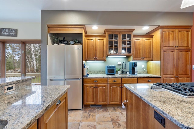 kitchen featuring light stone countertops, sink, light tile patterned floors, and stainless steel appliances