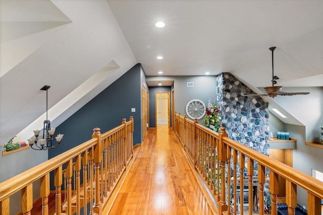 hallway featuring hardwood / wood-style flooring, lofted ceiling, and a chandelier