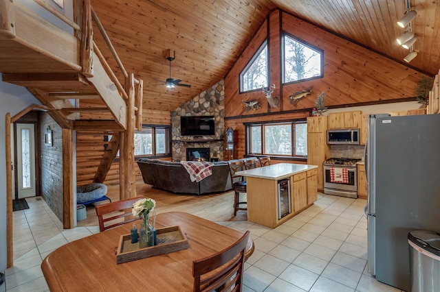 kitchen featuring stainless steel appliances, a wealth of natural light, wood ceiling, and a stone fireplace