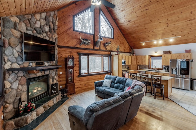 living room featuring plenty of natural light, wood ceiling, a fireplace, and light wood-style flooring