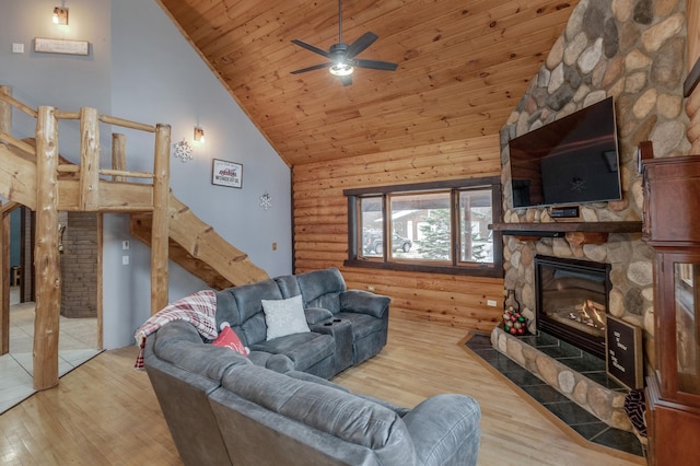 living area featuring rustic walls, wood ceiling, a stone fireplace, wood finished floors, and high vaulted ceiling