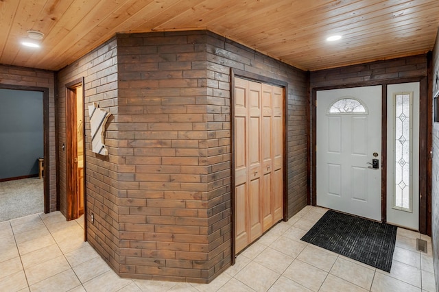 entrance foyer with light tile patterned floors, recessed lighting, visible vents, wood ceiling, and brick wall