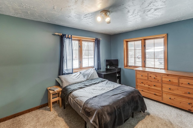 bedroom with light colored carpet, a textured ceiling, and baseboards