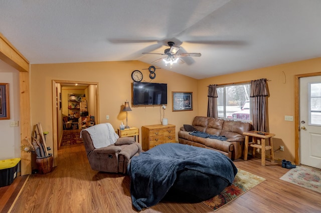 living area featuring lofted ceiling, light wood finished floors, and ceiling fan