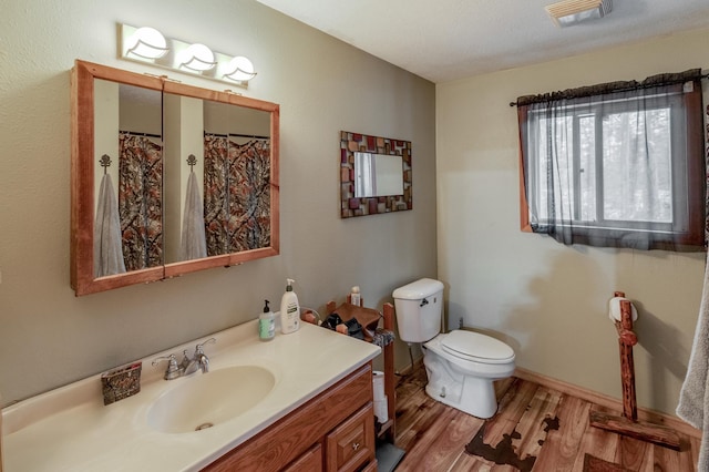 full bathroom with baseboards, visible vents, toilet, wood finished floors, and vanity