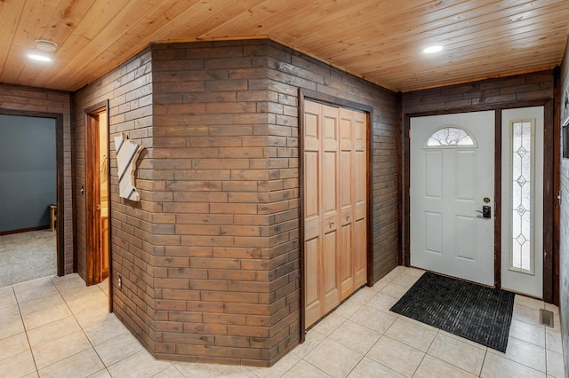 entryway with light tile patterned floors, recessed lighting, visible vents, wood ceiling, and brick wall