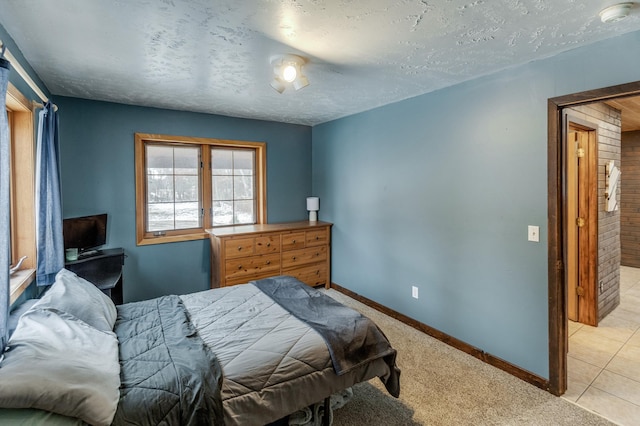 bedroom featuring light carpet, light tile patterned floors, baseboards, and a textured ceiling