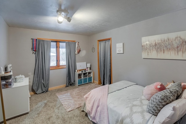 carpeted bedroom featuring a ceiling fan, a textured ceiling, baseboards, and a closet