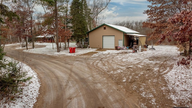 exterior space with a garage, a pole building, an outdoor structure, and dirt driveway