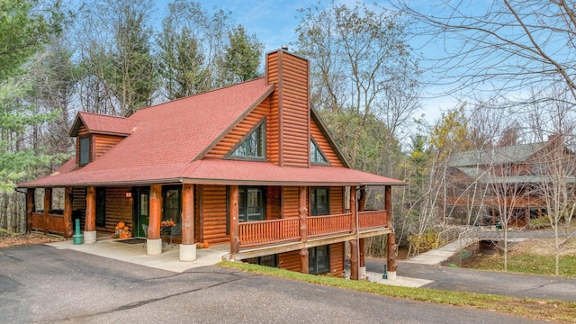 18061 County Highway Oo, Chippewa Falls, WI 54729 - view of front of property featuring covered porch, a chimney, log siding, and roof with shingles