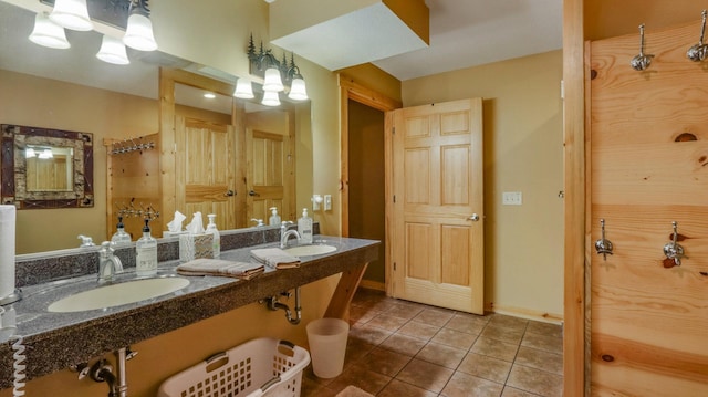 full bath featuring dual sinks, tile patterned flooring, and baseboards