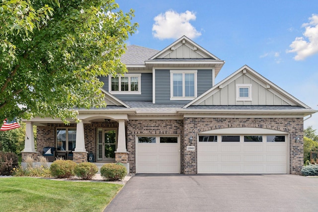 craftsman-style house with a garage, covered porch, and a front yard