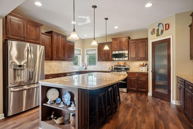 kitchen featuring a kitchen breakfast bar, dark wood-type flooring, a kitchen island, and stainless steel appliances