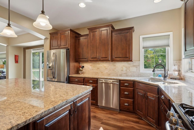 kitchen with appliances with stainless steel finishes, tasteful backsplash, sink, decorative light fixtures, and dark hardwood / wood-style floors