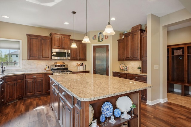 kitchen with dark hardwood / wood-style flooring, stainless steel appliances, sink, pendant lighting, and a kitchen island