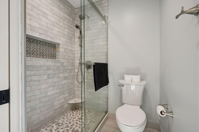 bathroom featuring toilet and a shower with door