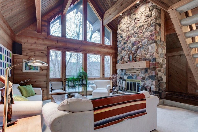 living room featuring a wealth of natural light, beam ceiling, a stone fireplace, and high vaulted ceiling